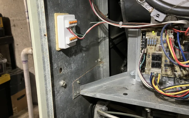 Small C wire adapter module mounted inside a furnace cabinet and wired to the control board