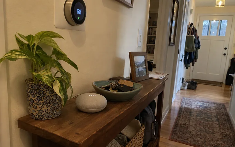 Smart speaker on a hallway table below a wall thermostat